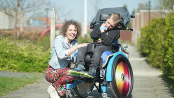 Medewerker en jonge cliënt met een meervoudige beperking in rolstoel poseren samen Medewerker en jonge cliënt met een meervoudige beperking in rolstoel poseren samen