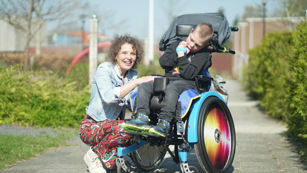 Medewerker en jonge cliënt met een meervoudige beperking in rolstoel poseren samen Medewerker en jonge cliënt met een meervoudige beperking in rolstoel poseren samen