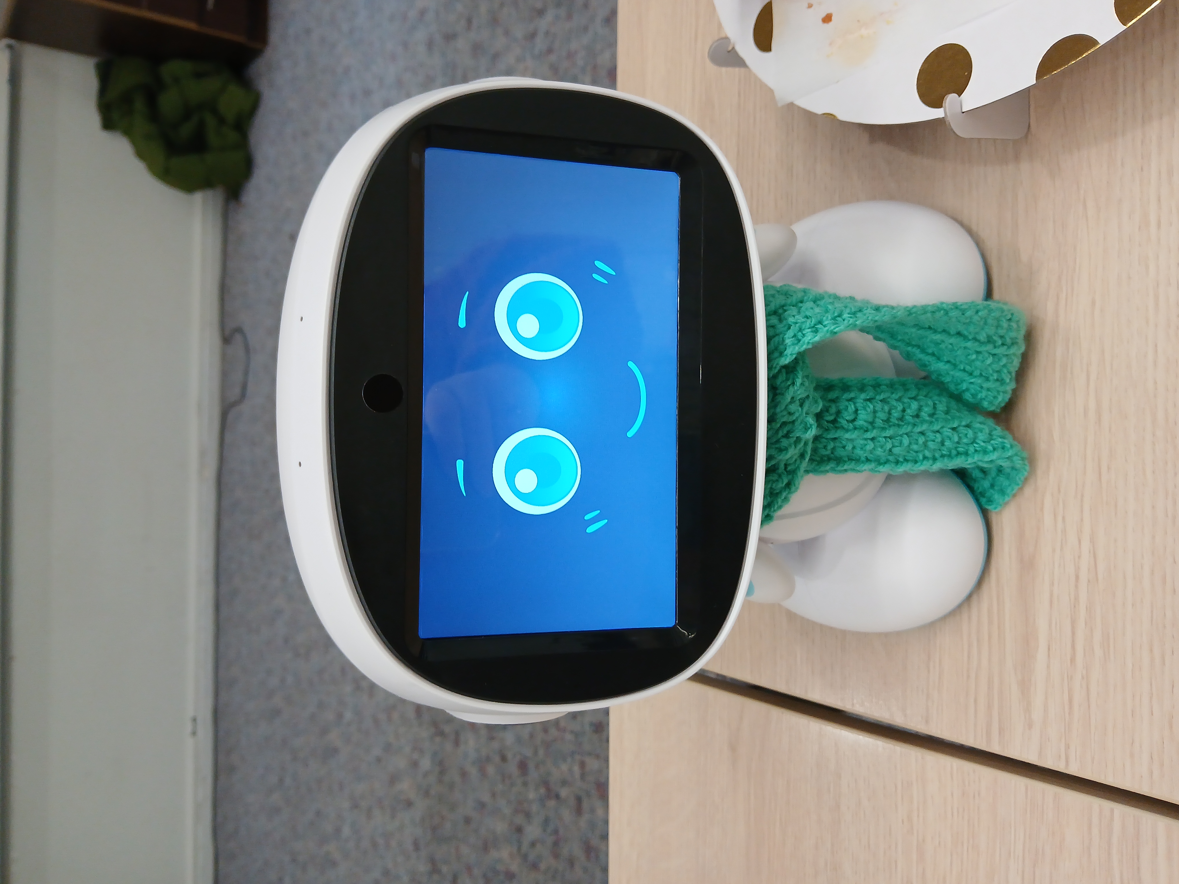 Een robotje met een rond hoofd en twee kleine voetjes. Het heeft een lachend gezichtje. 