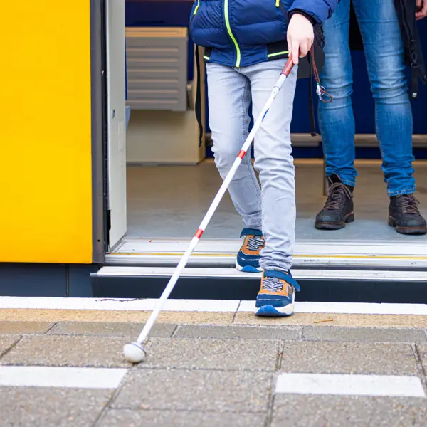 Een jongen stapt uit de trein met zijn taststok. Een jongen stapt uit de trein met zijn taststok.