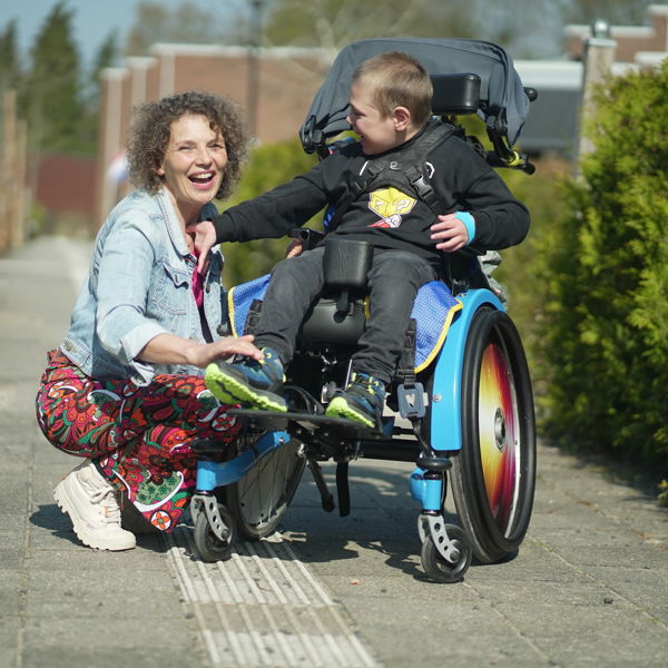 Medewerker en jonge cliënt met een meervoudige beperking in rolstoel poseren samen Medewerker en jonge cliënt met een meervoudige beperking in rolstoel poseren samen