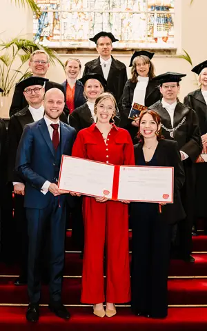 Sarah Tol poseert lachend met haar proefschrift na haar verdediging Sarah Tol poseert lachend met haar proefschrift na haar verdediging