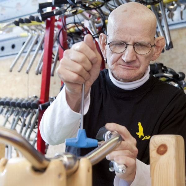 Cliënt van Visio sleutelt aan een stuur van een fiets als dagactiviteit Cliënt van Visio sleutelt aan een stuur van een fiets als dagactiviteit