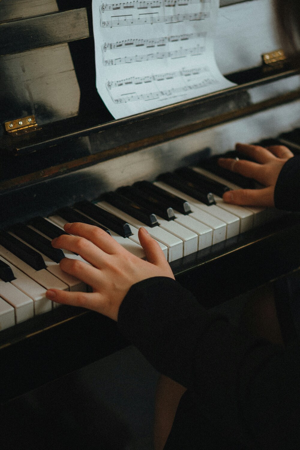 Dame speelt piano, je zien alleen haar handen op de toetsen en een stukje van de bladmuziek