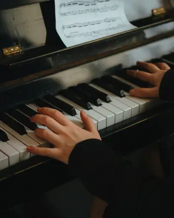Dame speelt piano, je zien alleen haar handen op de toetsen en een stukje van de bladmuziek Dame speelt piano, je zien alleen haar handen op de toetsen en een stukje van de bladmuziek