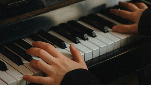 Dame speelt piano, je zien alleen haar handen op de toetsen en een stukje van de bladmuziek Dame speelt piano, je zien alleen haar handen op de toetsen en een stukje van de bladmuziek