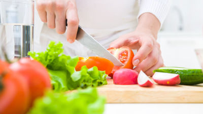 Een close=up van handen die een scherp met vasthouden en groenten snijden. Een close=up van handen die een scherp met vasthouden en groenten snijden.