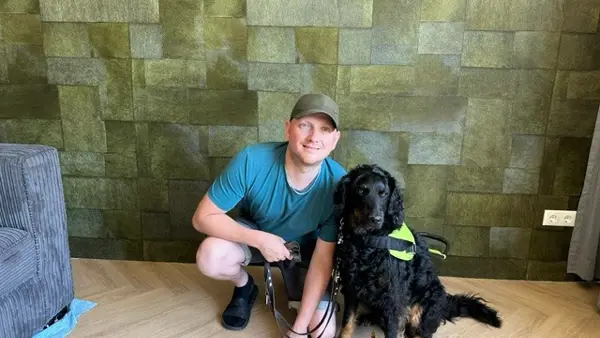 Theo van der Linden in een kamer samen met zijn blindegeleidehond Theo van der Linden in een kamer samen met zijn blindegeleidehond