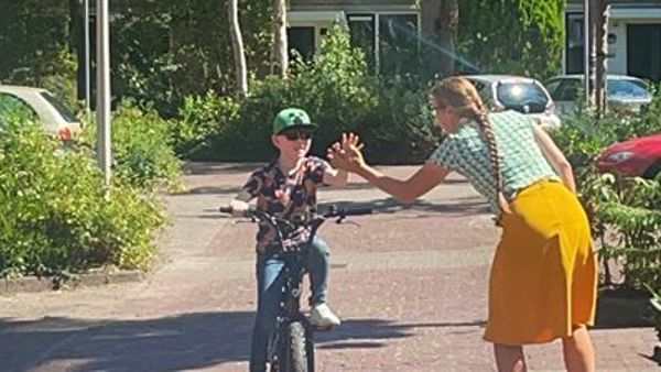 Huang zit op de fiets en geeft zijn ergotherapeut een high-five. Huang zit op de fiets en geeft zijn ergotherapeut een high-five.