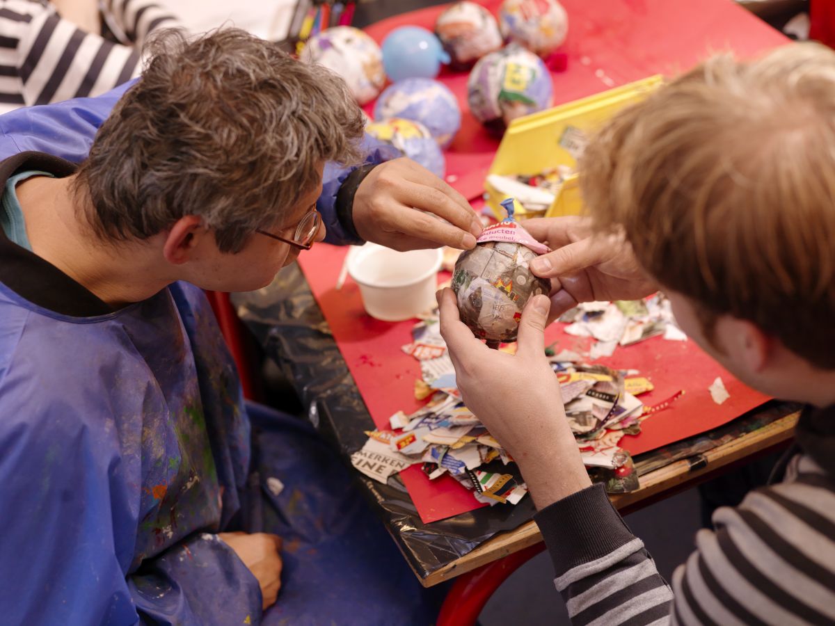 Twee mensen zijn samen creatief bezig met papier mache. 