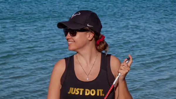 Marie-Elise poseert met haar taststok in een sportieve outfit met de tekst "Just do it" voor een meer met bergen op de achtergrond Marie-Elise poseert met haar taststok in een sportieve outfit met de tekst "Just do it" voor een meer met bergen op de achtergrond