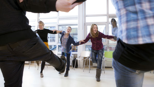 Leerlingen dansen samen in een kring. Leerlingen dansen samen in een kring.