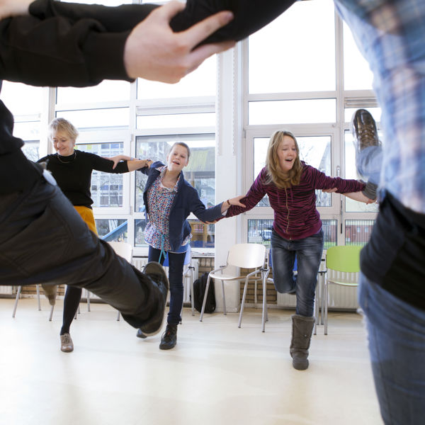 Leerlingen dansen samen in een kring. Leerlingen dansen samen in een kring.