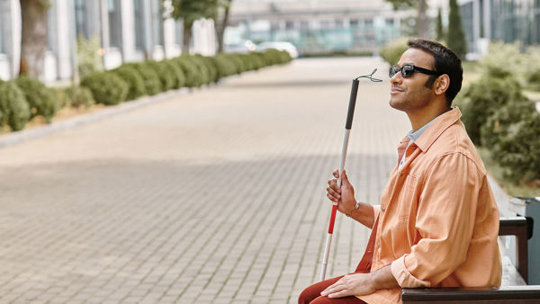 Blinde man met taststok op de bank Blinde man met taststok op de bank