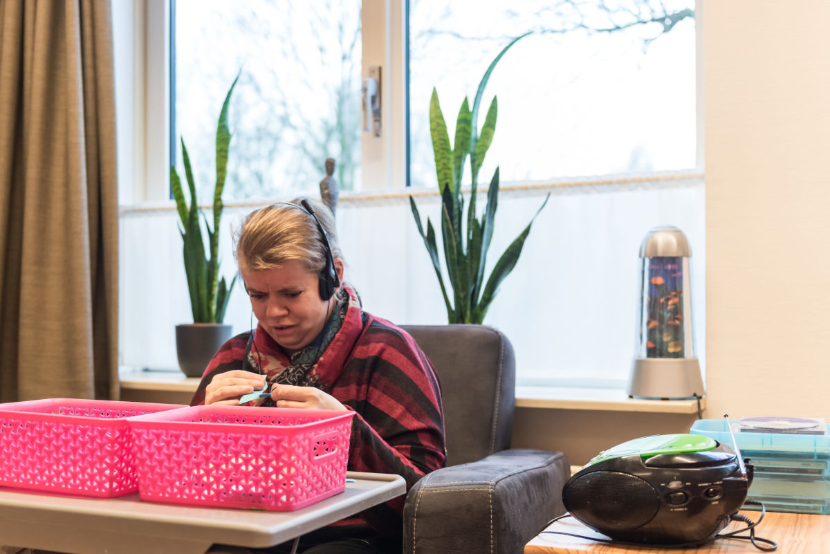 Cliënt zit in stoel en luister muziek met een koptelefoon