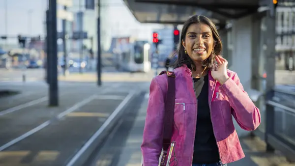 Visio-ambassadeur Bodhi Sripal staat bij een tramhalte met haar taststok. De foto laat zien hoe Bodhi als slechtziende jongvolwassen vrouw zelfstandig gebruikmaakt van het openbaar vervoer. Visio-ambassadeur Bodhi Sripal staat bij een tramhalte met haar taststok. De foto laat zien hoe Bodhi als slechtziende jongvolwassen vrouw zelfstandig gebruikmaakt van het openbaar vervoer.