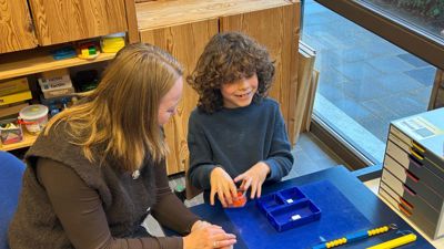 Jonah is samen met een begeleider aan het werk met de braille Rekenbox. Jonah is samen met een begeleider aan het werk met de braille Rekenbox.