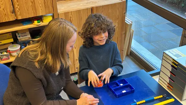 Jonah is samen met een begeleider aan het werk met de braille Rekenbox. Jonah is samen met een begeleider aan het werk met de braille Rekenbox.