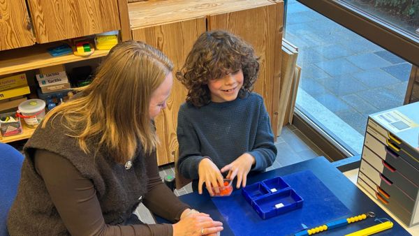 Jonah is samen met een begeleider aan het werk met de braille Rekenbox. Jonah is samen met een begeleider aan het werk met de braille Rekenbox.