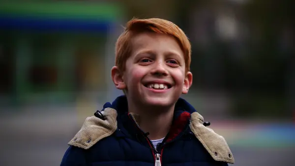 Kind met de aandoening CVI staat lachend op de foto Kind met de aandoening CVI staat lachend op de foto