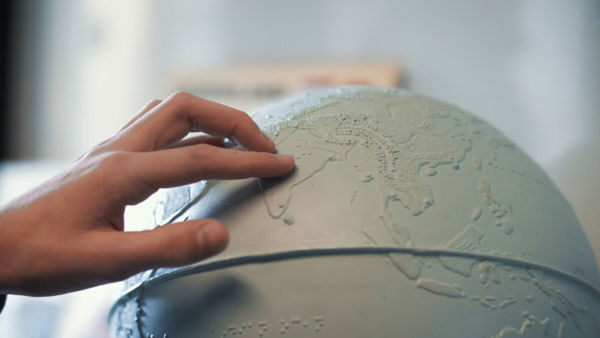 Een hand voelt aan een tactiele wereldbol. Een hand voelt aan een tactiele wereldbol.