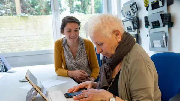 Oudere vrouw krijgt advies op het gebied tablet en telefoongebruik Oudere vrouw krijgt advies op het gebied tablet en telefoongebruik