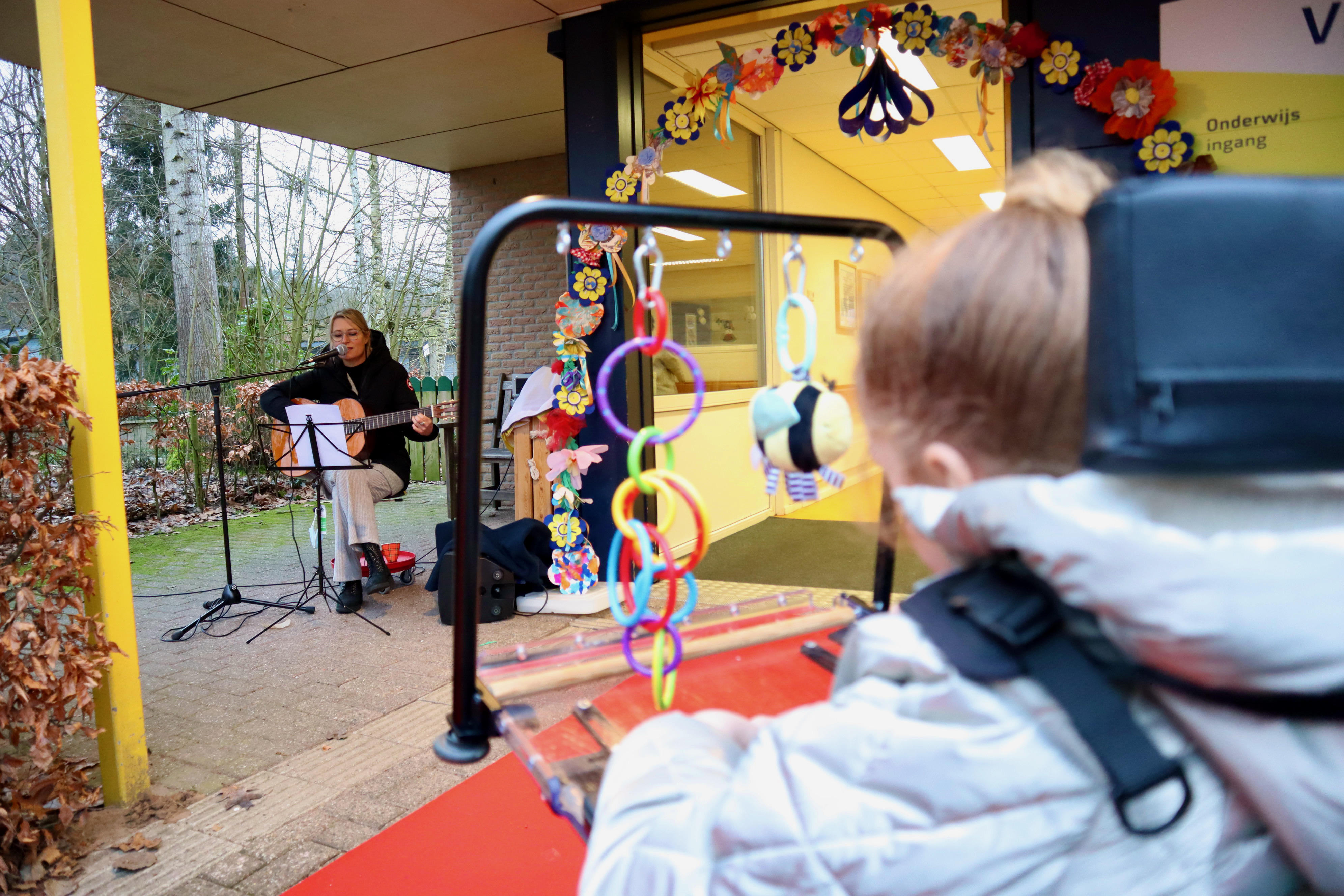 Kindje kijkt naar een docent die muziek maakt. 