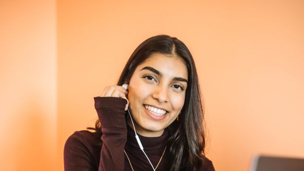 Bodhi zit op haar bed met haar laptop. Ze doet een oordopje, aangesloten aan haar laptop, in haar oor. Bodhi zit op haar bed met haar laptop. Ze doet een oordopje, aangesloten aan haar laptop, in haar oor.
