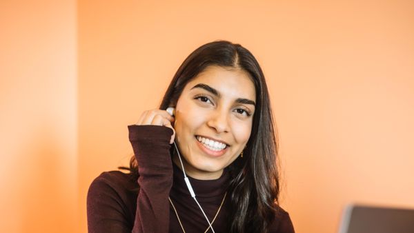 Bodhi zit op haar bed met haar laptop. Ze doet een oordopje, aangesloten aan haar laptop, in haar oor. Bodhi zit op haar bed met haar laptop. Ze doet een oordopje, aangesloten aan haar laptop, in haar oor.