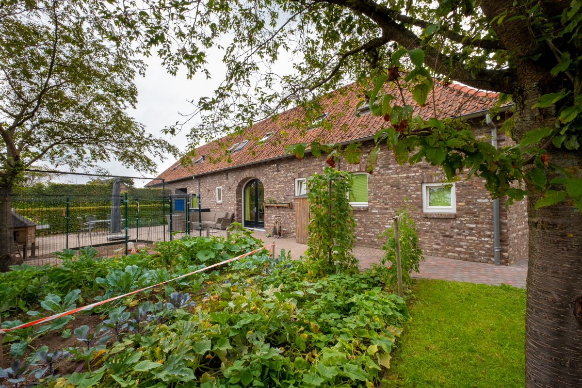 Gevel van de Hoeve omringd door groen bij Visio Wonen & Dagbesteding Stramproy