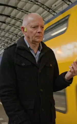 Fred loopt op station. Hij heeft oordopjes in, en heeft zijn telefoon in de hand. Fred loopt op station. Hij heeft oordopjes in, en heeft zijn telefoon in de hand.