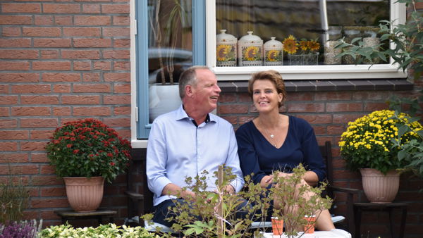 Renate en Jan zitten samen op een bankje in de tuin. Ze zijn omringd door planten. Renate en Jan zitten samen op een bankje in de tuin. Ze zijn omringd door planten.