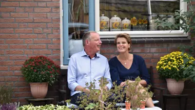 Renate en Jan zitten samen op een bankje in de tuin. Ze zijn omringd door planten. Renate en Jan zitten samen op een bankje in de tuin. Ze zijn omringd door planten.