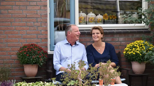 Renate en Jan zitten samen op een bankje in de tuin. Ze zijn omringd door planten. Renate en Jan zitten samen op een bankje in de tuin. Ze zijn omringd door planten.