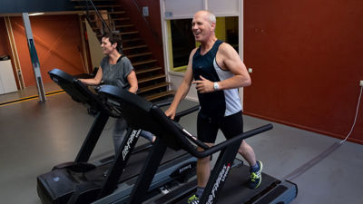 Een man en een vrouw staan beide op een loopband. Een man en een vrouw staan beide op een loopband.