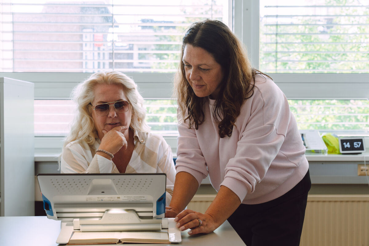 Visio medewerker geeft advies en training aan slechtziende vrouw