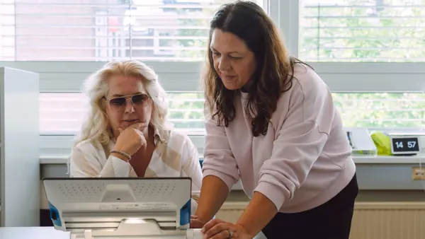 Visio medewerker geeft advies en training aan slechtziende vrouw Visio medewerker geeft advies en training aan slechtziende vrouw