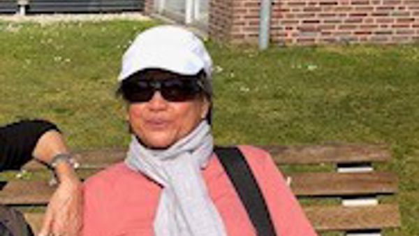 Maureen zit op een bankje in de zon. Ze draagt een pet en een zonnebril. Maureen zit op een bankje in de zon. Ze draagt een pet en een zonnebril.