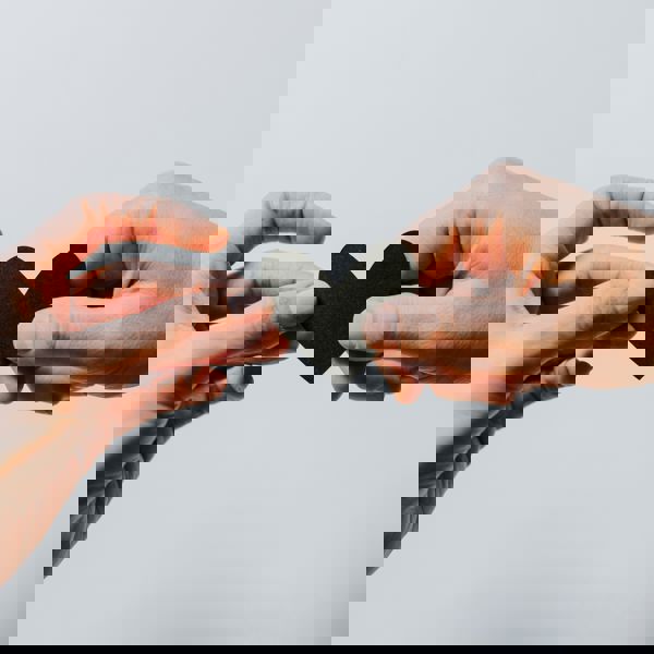 Twee handen houden een papieren hartje vast Twee handen houden een papieren hartje vast