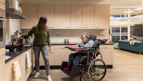 Cliënt in rolstoel en medewerker samen in een keuken van Visio Wonen & Dagbesteding Meppel Cliënt in rolstoel en medewerker samen in een keuken van Visio Wonen & Dagbesteding Meppel
