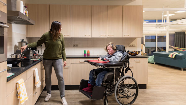 Cliënt in rolstoel en medewerker samen in een keuken van Visio Wonen & Dagbesteding Meppel Cliënt in rolstoel en medewerker samen in een keuken van Visio Wonen & Dagbesteding Meppel