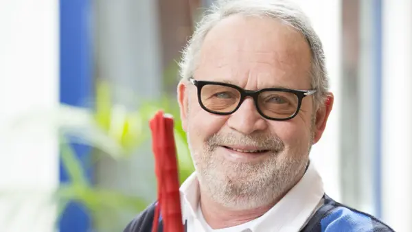 Oudere man met glaucoom glimlacht zittend met een taststok in zijn hand Oudere man met glaucoom glimlacht zittend met een taststok in zijn hand