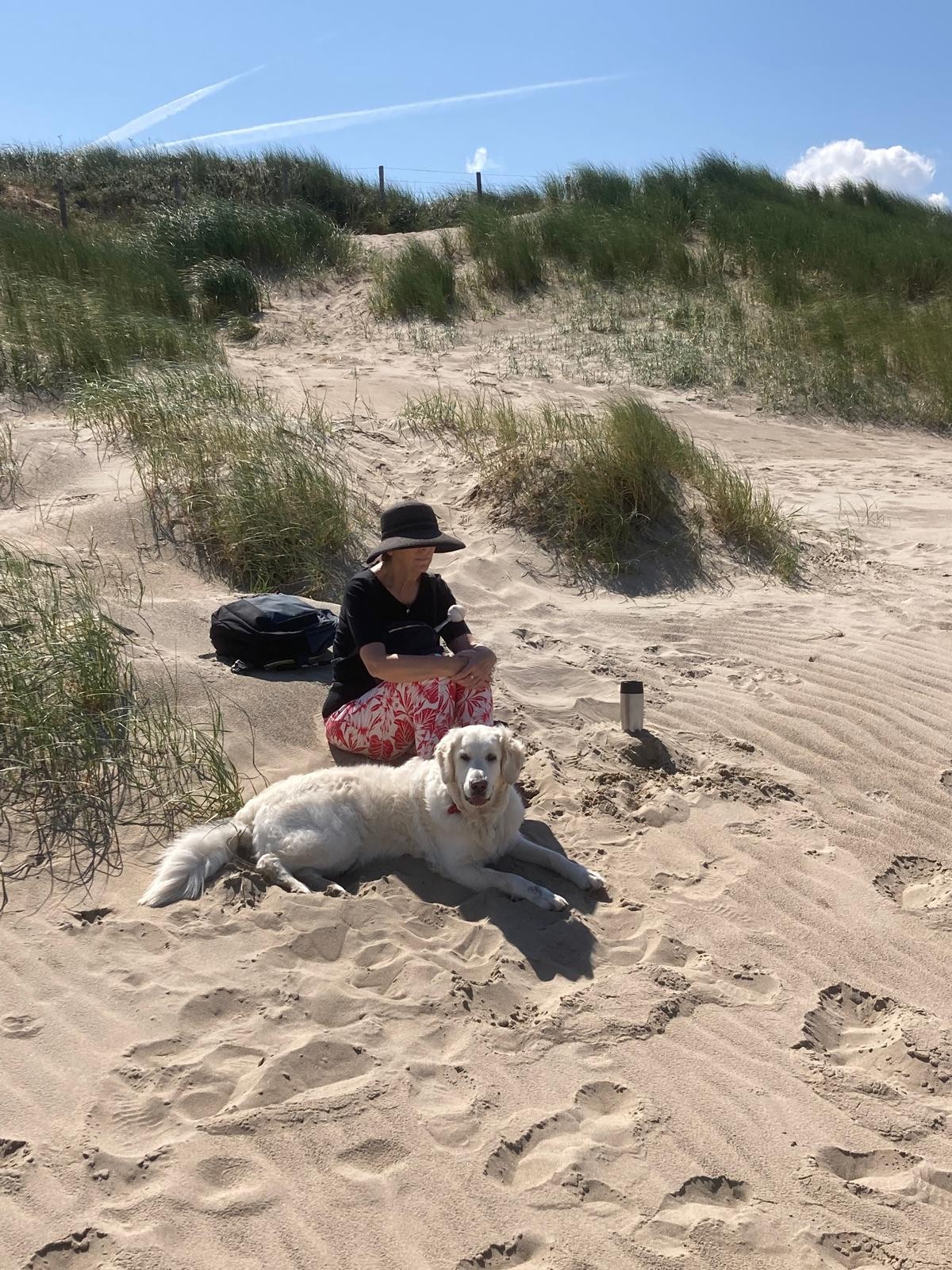 Sabrina zit op het strand met haar geleidenhond 