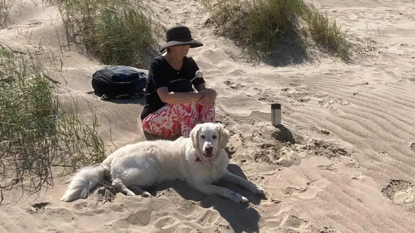 Sabrina zit op het strand met haar geleidenhond Sabrina zit op het strand met haar geleidenhond