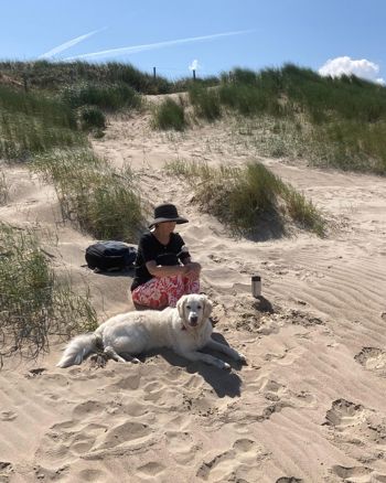Sabrina zit op het strand met haar geleidenhond Sabrina zit op het strand met haar geleidenhond