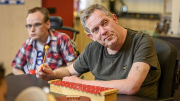 Cliënt met een visuele en verstandelijke beperking speelt op een xylofoon Cliënt met een visuele en verstandelijke beperking speelt op een xylofoon