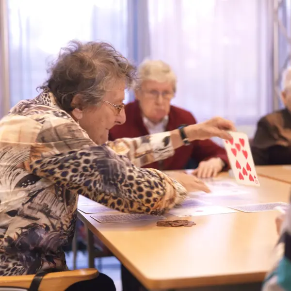Een groepje ouderen speelt een kaartspel. De kaarten zijn extra groot met grote opdruk. Een groepje ouderen speelt een kaartspel. De kaarten zijn extra groot met grote opdruk.