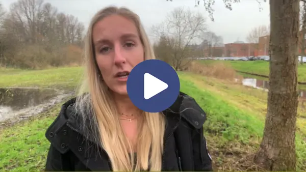 Een blonde vrouw staat in de natuur. Ze kijkt naar de camera en is aan het praten. Er staat een playbutton op de afbeelding. Een blonde vrouw staat in de natuur. Ze kijkt naar de camera en is aan het praten. Er staat een playbutton op de afbeelding.