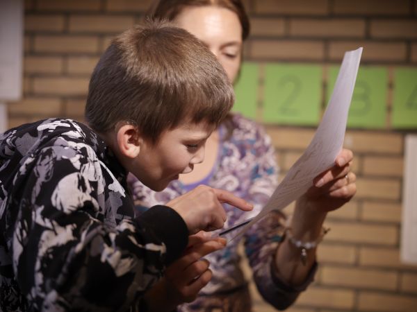 Slechtziende jongen leest iets van blad Slechtziende jongen leest iets van blad