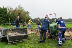 Foto met vrijwilligers van Nuon die helpen met een kruiwagen op het terrein van Visio De Brink. Foto met vrijwilligers van Nuon die helpen met een kruiwagen op het terrein van Visio De Brink.